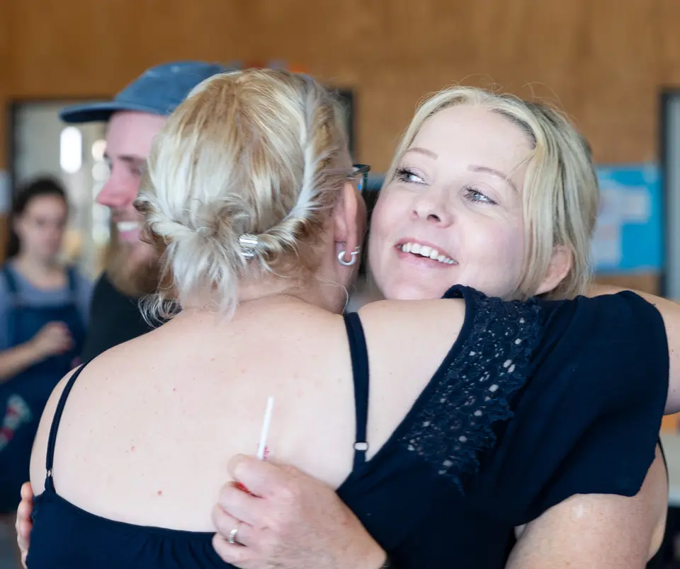 Two women hugging hello at Rhythm Church on a Sunday